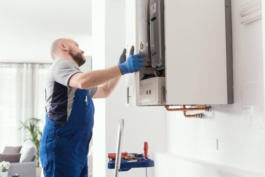 A man in overalls and gloves repairs a gas boiler focused on his task in a well-lit utility room