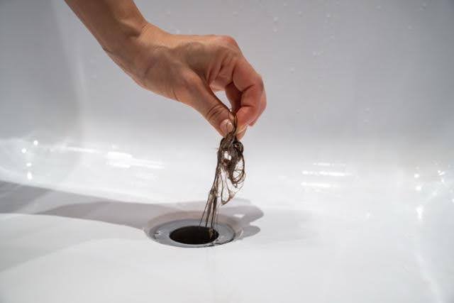 A person holds a piece of metal over a sink preparing to clean or inspect it