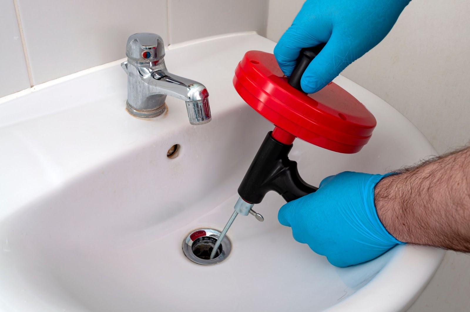 A close-up of a worker's hands using a specialized tool to press a copper fitting onto a pipe, part of a modern plumbing installation.