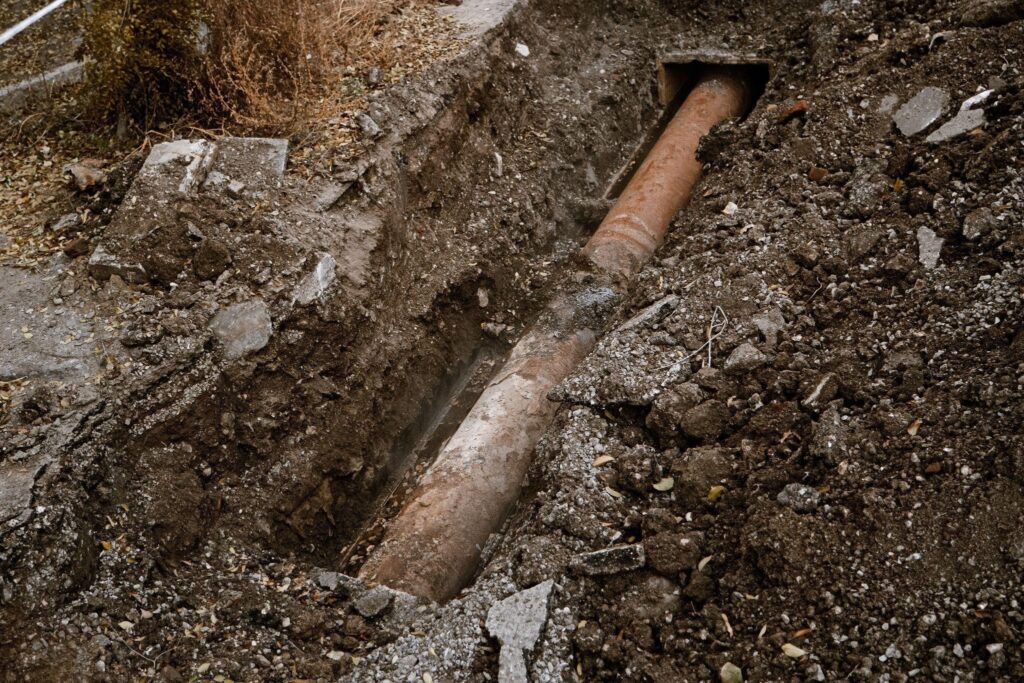 A buried pipe is visible beside a wooden fence indicating local utility infrastructure